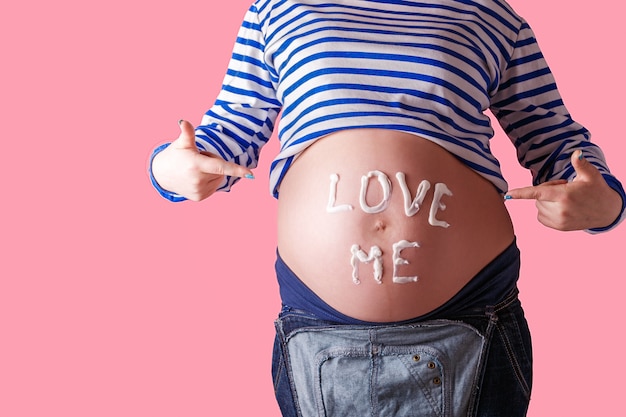 Donna incinta che scrive la parola "amami" sulla sua pancia.