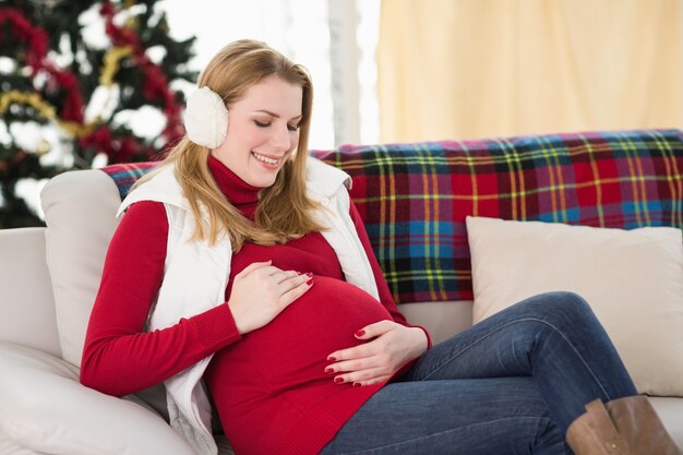 Donna incinta che sfrega la sua pancia sul divano