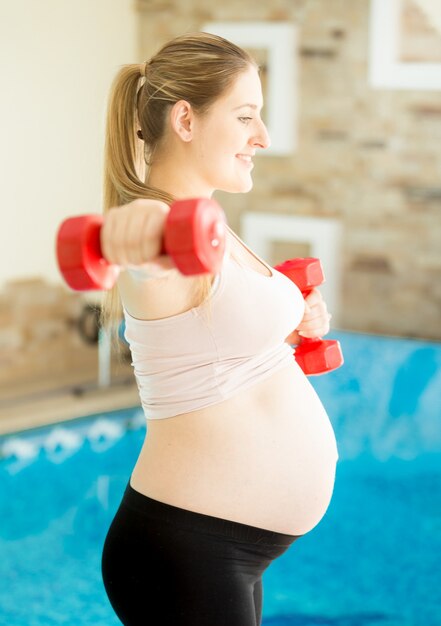 Donna incinta che si esercita con i manubri in palestra