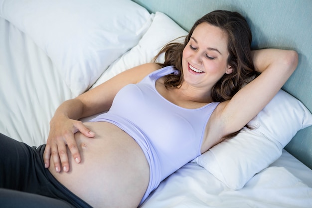 Donna incinta che si trova a letto a casa