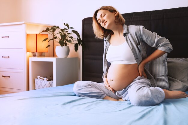 donna incinta che soffre di mal di schiena o mal di testa donna che ha contrazioni e mal di schiena a casa