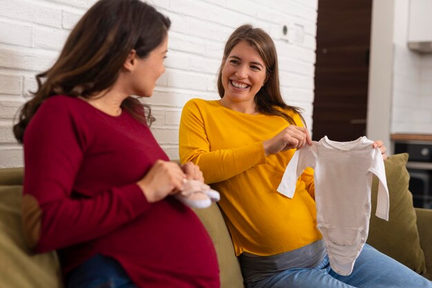 Donna incinta che tiene il body bianco del bambino che si prepara alla nascita del bambino durante la gravidanza