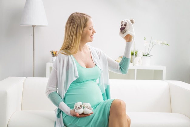 Donna incinta che tiene il cappello e le scarpe del bambino