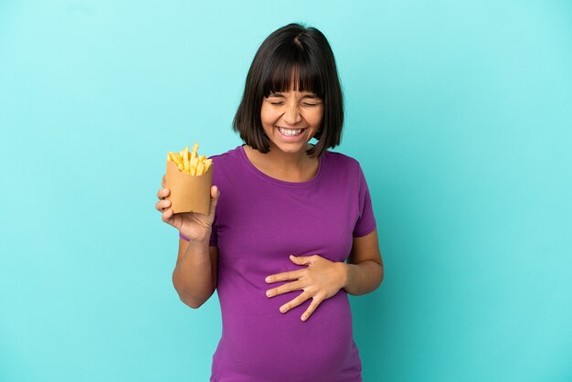 Donna incinta che tiene patatine fritte su sfondo isolato sorridendo molto