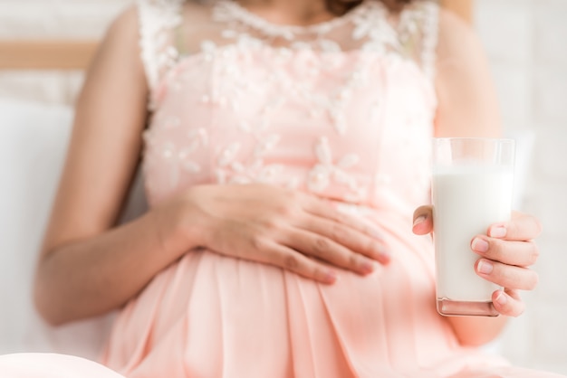 Donna incinta che tiene un bicchiere di latte fresco