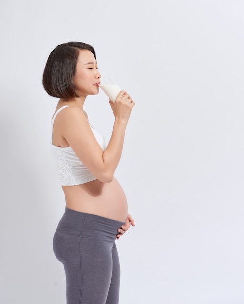 Donna incinta che tiene un bicchiere di latte in mano buona salute, isolato su sfondo bianco.