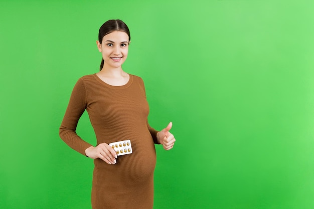 Donna incinta che tiene un mucchio di blister di pillole su sfondo colorato con spazio per la copia Vitamine durante la gravidanza concetto