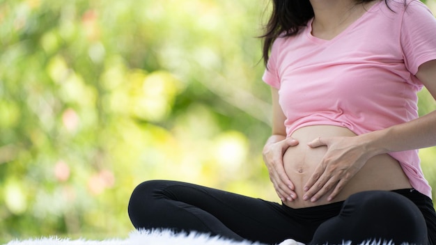 Donna incinta che tocca la pancia nel parco cittadino Incinta Rilassamento ed esercizio Bella foto d'umore tenero della gravidanza