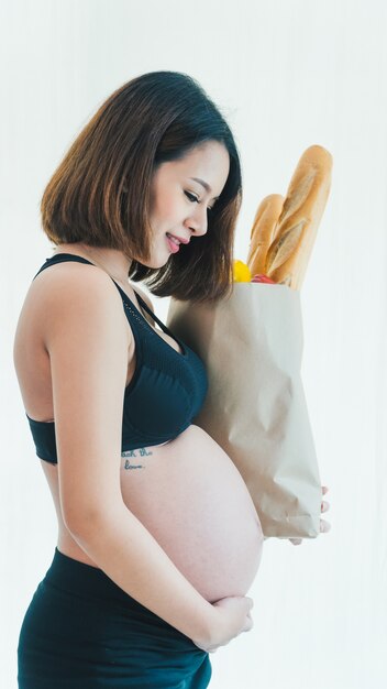 Donna incinta che trasporta un sacchetto di cibo.