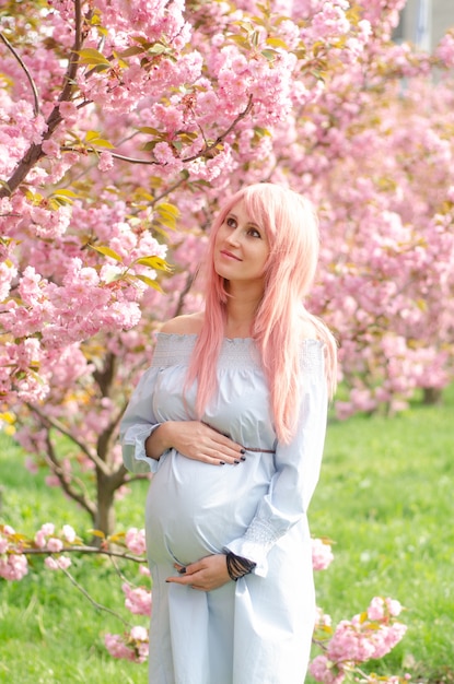 Donna incinta con albero in fiore. Concetto di maternità, gravidanza e aspettativa.