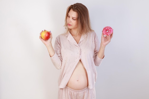 Donna incinta con ciambelle e concetto di cibo sano mela