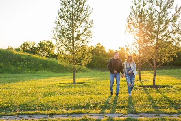 Donna incinta con il marito che cammina sul prato alla luce del sole