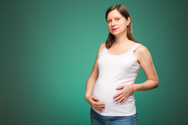 Donna incinta con la pancia grande e l'espressione del viso felice, in attesa della nascita di un bambino. Femmina felice con una grande pancia, tempo di gravidanza sano.