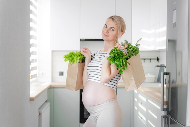 Donna incinta con pacchetti di erbe fresche frullati verdi il concetto di cibo sano e sano per le donne in gravidanza