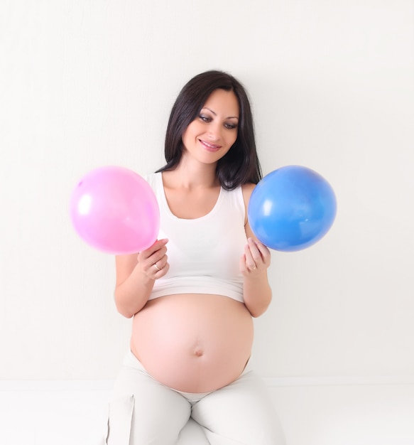 Donna incinta con palloncino blu e rosa