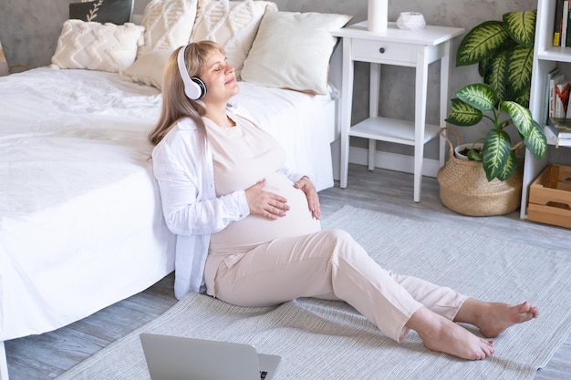 donna incinta con pancia grande gravidanza avanzata in cuffia senza fili che ascolta musica