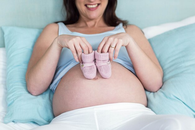 Donna incinta con pantofole a maglia sulla sua pancia nella sua camera da letto