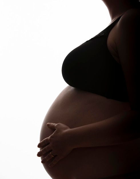 Donna incinta con un pancione stagliato su uno sfondo bianco