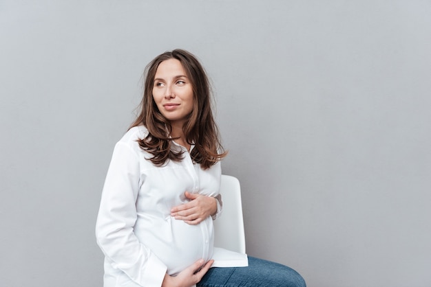 Donna incinta di bellezza che distoglie lo sguardo in studio isolato sfondo grigio