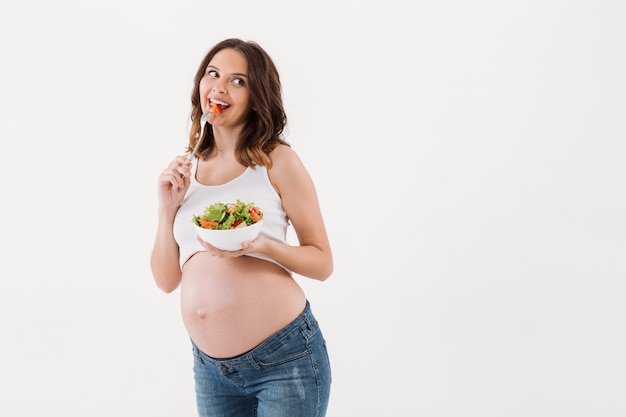 Donna incinta felice che mangia insalata di vitamine