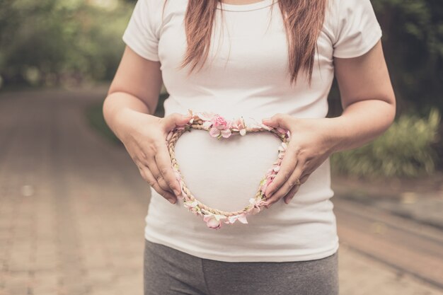 Donna incinta felice e fiera che tiene la sua pancia in un parco