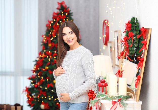 Donna incinta felice nella stanza decorata per Natale