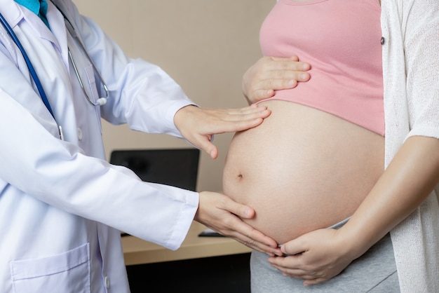 Donna incinta felice visita medico ginecologo in ospedale o in clinica per consulente di gravidanza.