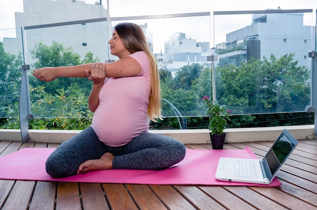 Donna incinta in classe di yoga che fa allungamenti del braccio