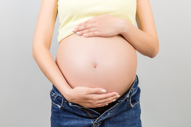 donna incinta in jeans decompressi che mostra il suo pancione