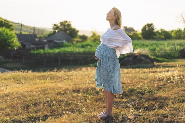 Donna incinta in piedi nel campo