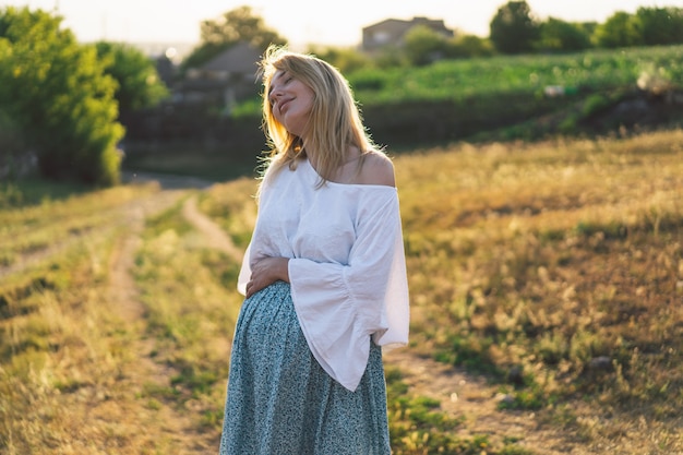 Donna incinta in piedi nel campo