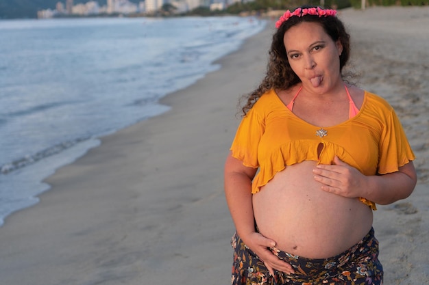 Donna incinta in posa in piedi sulla spiaggia