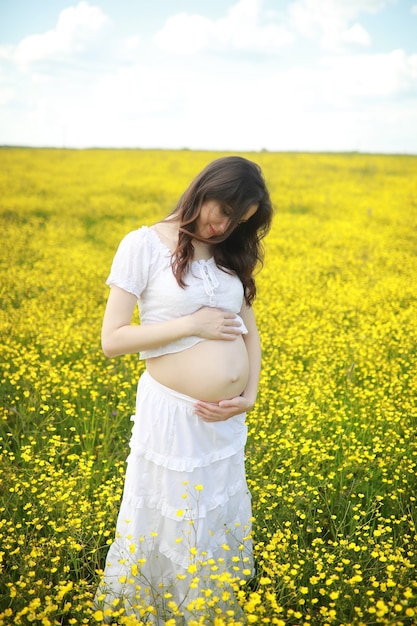 Donna incinta in un vestito in un campo di fiori