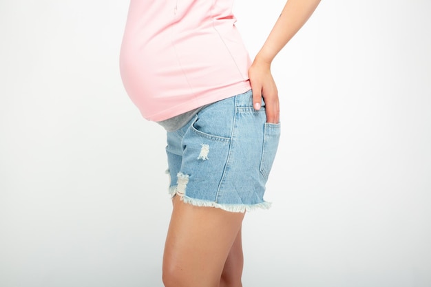 Donna incinta in una camicia rosa e pantaloncini blu