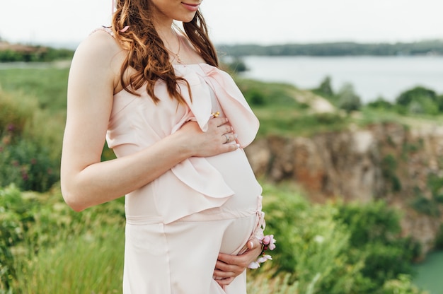 Donna incinta in vestito rosa che si rilassa all'aperto