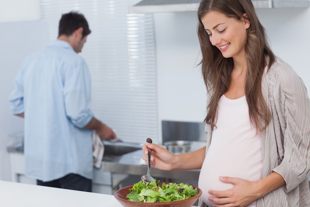 Donna incinta mescolando un&#39;insalata in cucina