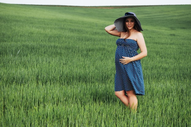 Donna incinta nel campo di grano verde