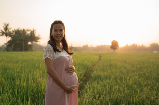 Donna incinta nel giacimento del riso il giorno del tramonto