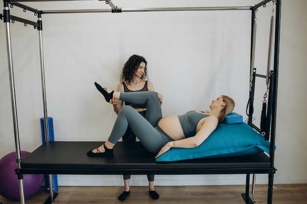 Donna incinta pilates esercizio allenamento in palestra con personal trainer