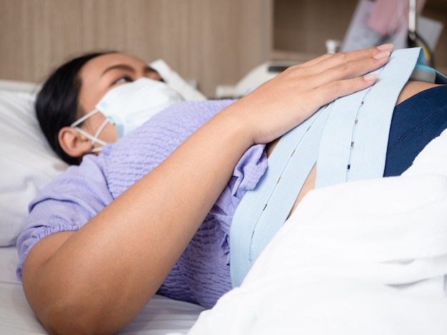 Donna incinta sdraiata sul letto in attesa che il medico controlli il bambino