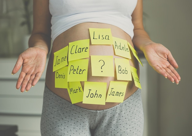 Donna incinta tonica con nomi di bambini sulla pancia