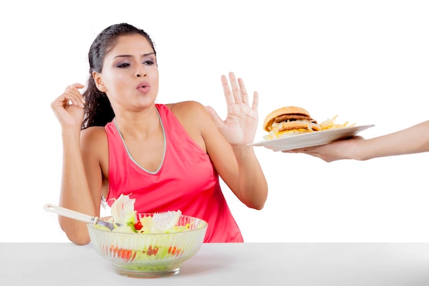 Donna indiana che mangia insalata sana e rifiuta l'hamburger isolato su sfondo bianco