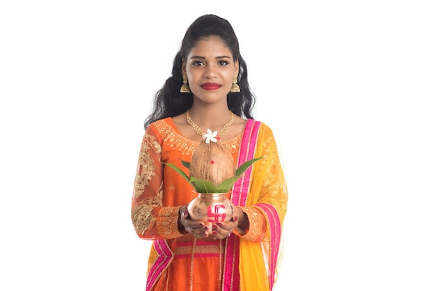 Donna indiana che tiene un tradizionale Kalash di rame con cocco e foglia di mango con decorazioni floreali, essenziale nel festival e nel culto indiano indù