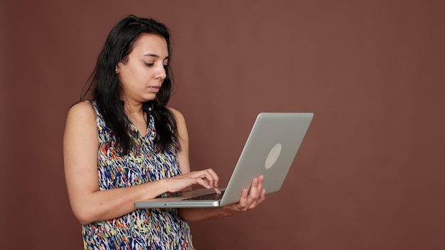 Donna indiana che utilizza il laptop per controllare il sito Web online sulla rete, navigando nell'app Internet per l'intrattenimento. Scorrendo il web dei social media sul computer, la tecnologia del PC wireless sullo schermo.