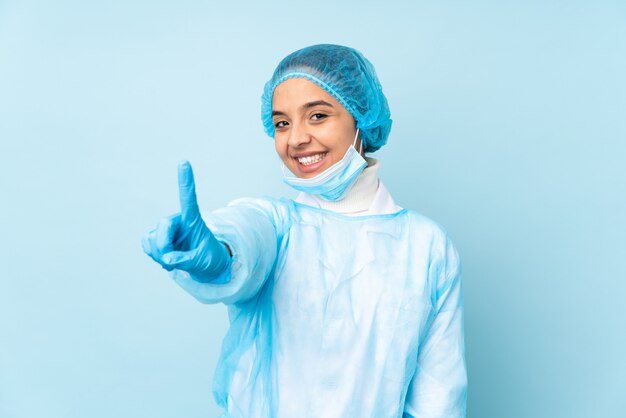 Donna indiana del giovane chirurgo in uniforme blu che mostra e che solleva un dito