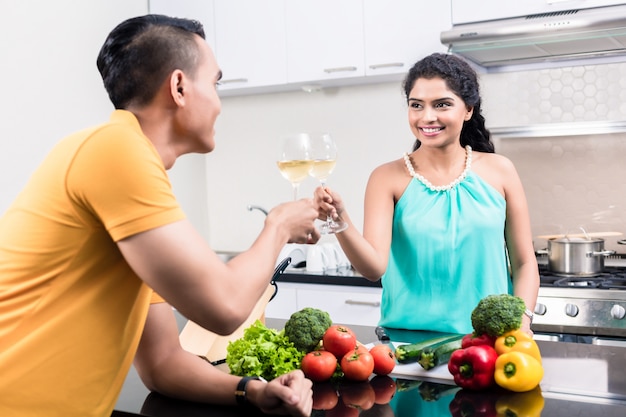 Donna indiana e uomo in cucina con vino rosso