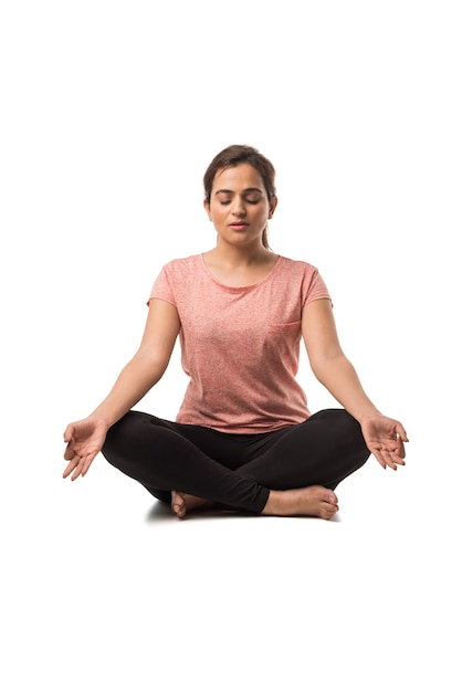 Donna indiana o ragazza che esegue asana yoga o meditazione o dhyana seduta isolate su sfondo bianco white