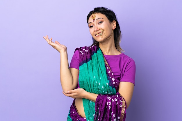 Donna indiana sul muro viola tendendo le mani al lato per invitare a venire