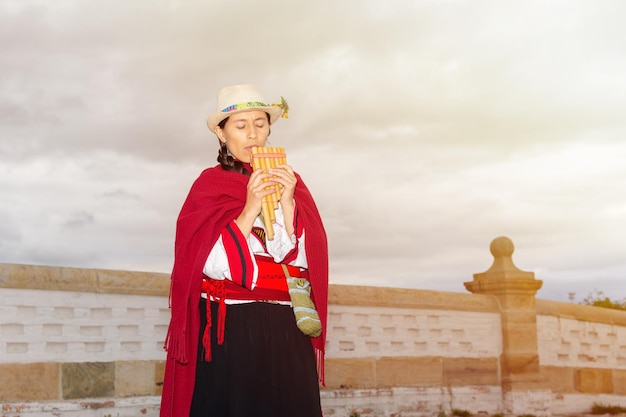 Donna indigena latinoamericana con cappello e scialle che suona la cornamusa