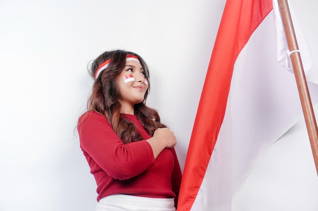 Donna indonesiana saluta con un gesto orgoglioso mentre tiene in mano la bandiera dell'Indonesia